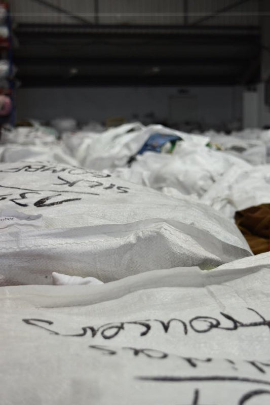 View of warehouse filled with large white-bagged bales containing clothing. Image taken by HOTCAKES vintage clothes pickers during picking visit