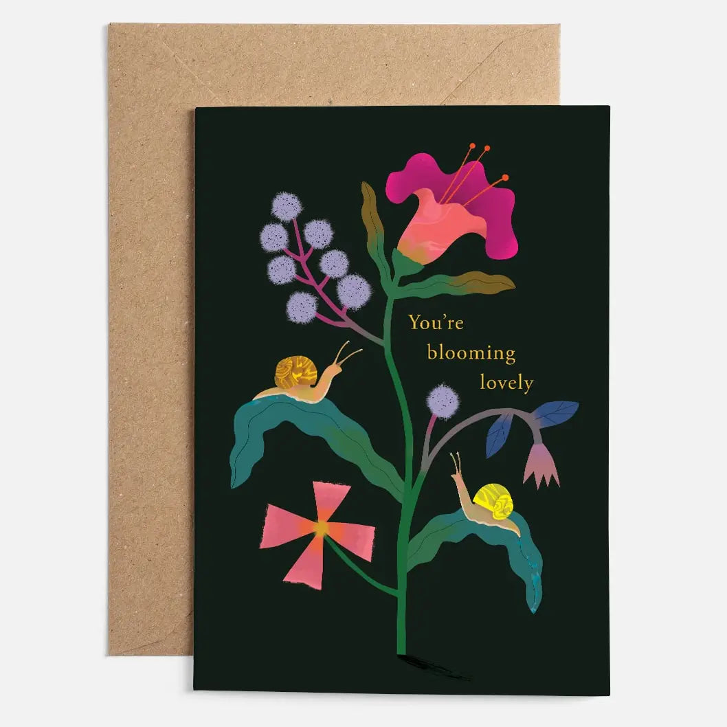 Greeting card with floral design and snails on a black background, accompanied by a brown envelope.