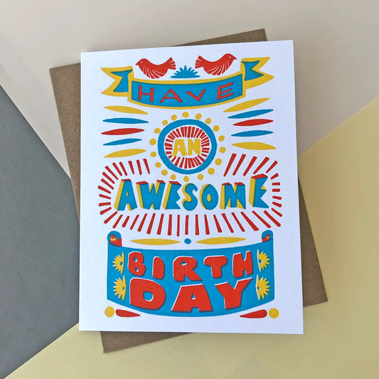 A yellow, blue and red birthday card with the words ' Have an awsome birthday ' written on the front in different fonts