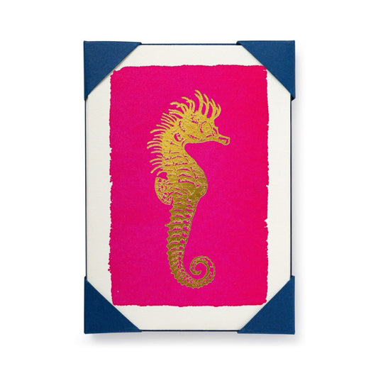 A pack of greeting cards with a gold seahorse design on a pink background, with a white envelope.