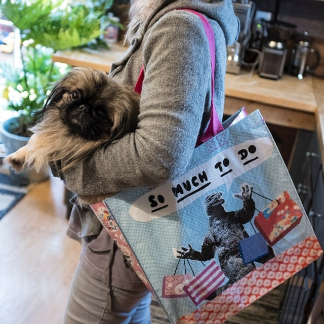 Someone wearing a Blue Q ‘so much to do’ shopper whilst also holding a little dog