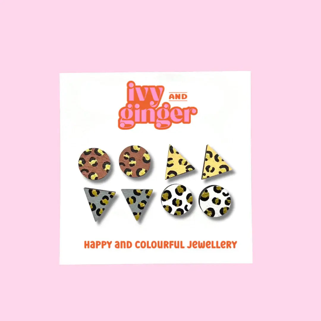 A set of hand-painted gold leopard print wooden earrings, presented on a card with the Ivy and Ginger brand logo.