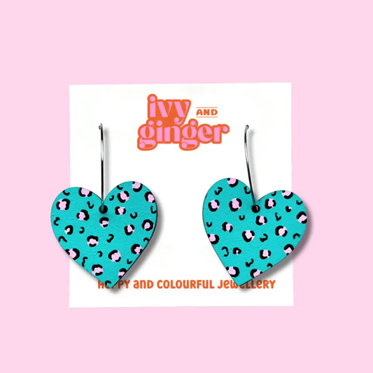 Blue wooden heart shaped earrings with a pink leopard print that are displayed on a white backing card.