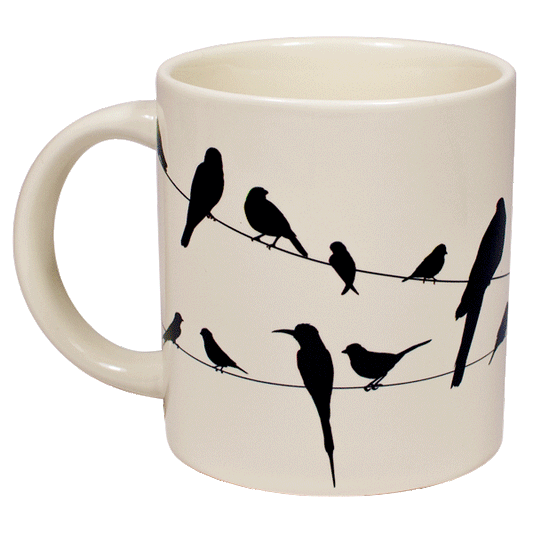 A cream mug with silhouettes of birds on a wire all over, when hot water is poured in they become colourful 