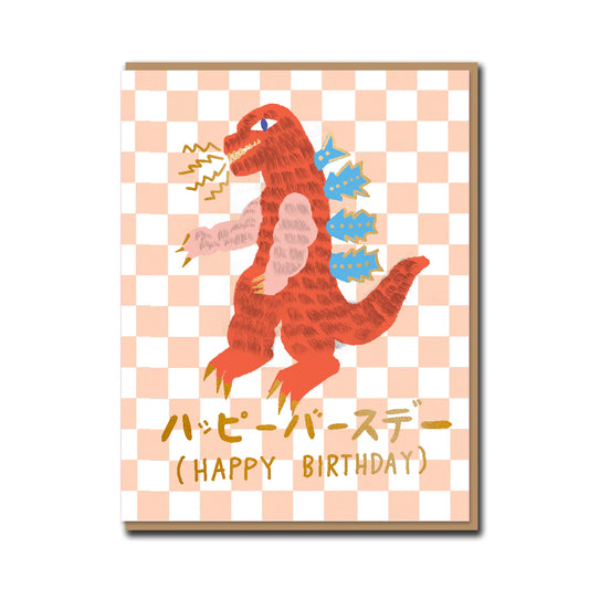 A pink and white checkered birthday card with a red and blue monster on the front. The text underneath the monster reads 'Happy Birthday' 