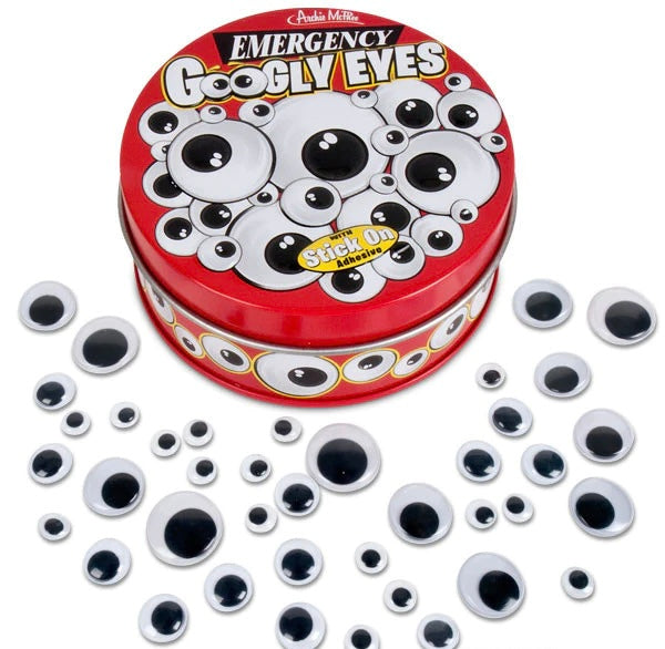 A red tin of emergency googly eyes that is surrounded by lots of different sized googly eyes.
