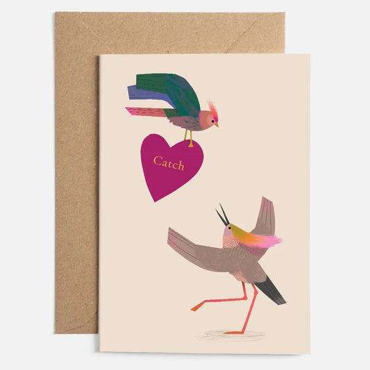 Two colourful stylized birds, one is holding a purple heart that says Catch and its printed on a beige card.