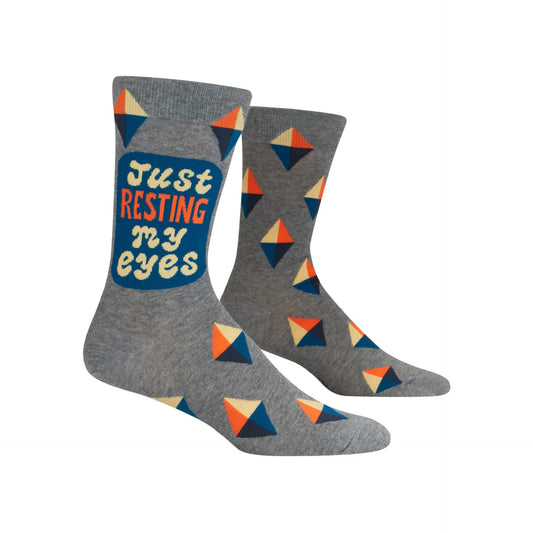 A pair of socks with a geometric pattern and the text 'Just Resting My Eyes' on them.