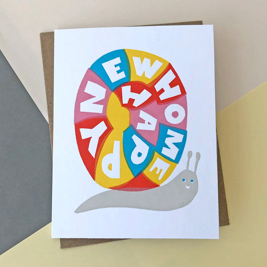 A new home card with a colourful snail on the front. It has text on the snails shell that reads ' Happy new home ' 