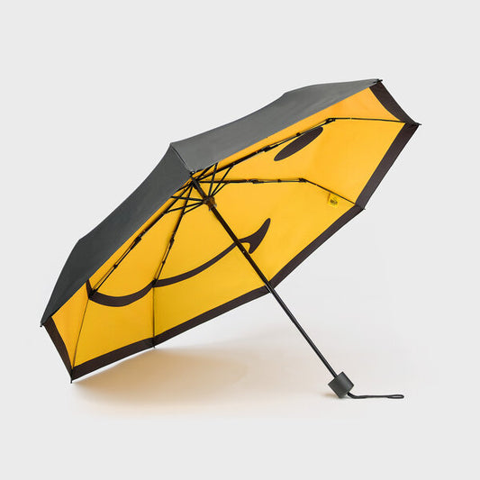 A black open umbrella with a yellow smiley face on the inside