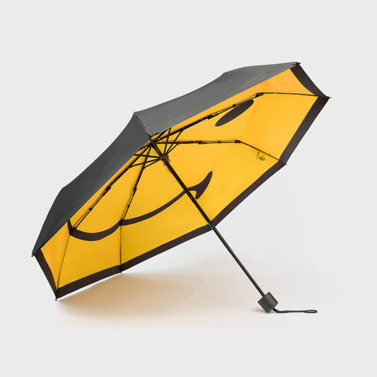 A black open umbrella with a yellow smiley face on the inside 