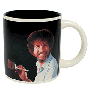 A mug with Picture of Bob Ross on. In the background it is black but shows it changes to one of his scenic paintings when filled with a hot liquid