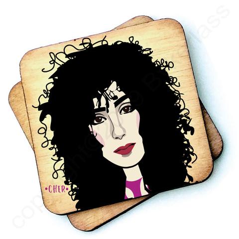 Image shows a wooden drinks coaster with a cartoon graphic of Cher on the front 
