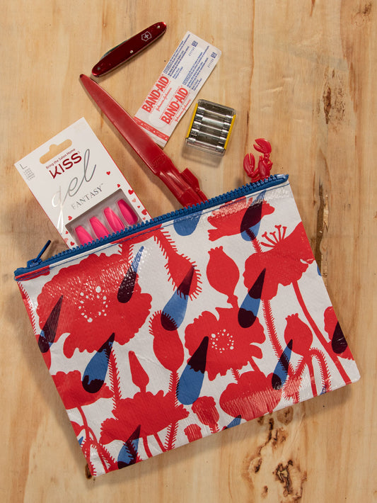 A white Blue Q zipper pouch with a blue zip. On the pouch are Red poppys in various stages of bloom and blue raindrops 
