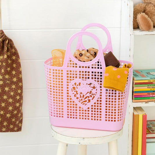 A pink plastic basket with a love heart and flower design on . The basket is filled with various household items 