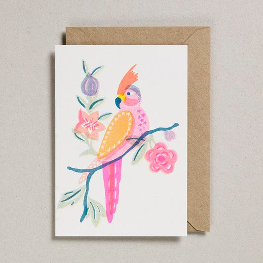 A white card with a print on of a pink and orange parrot perched on a branch. The branch is blue with pink and purple flowers coming off it.