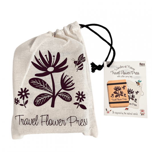 A travel flower press in a white fabric bag. The bag has a purple flower in the middle and reads 'Travel flower press' underneath 