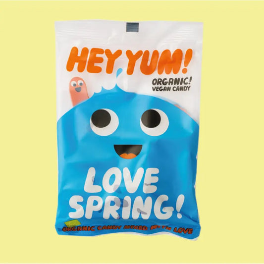 A sweet packet with a blue character on the front and a smiley worm. The text reads: Hey Yum! Organic vegan candy