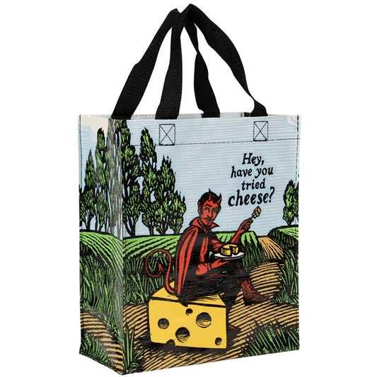 A Blue Q lunch bag with the devil sat on a block of cheese in a field. The text reads: 'Hey, have you tried cheese?'