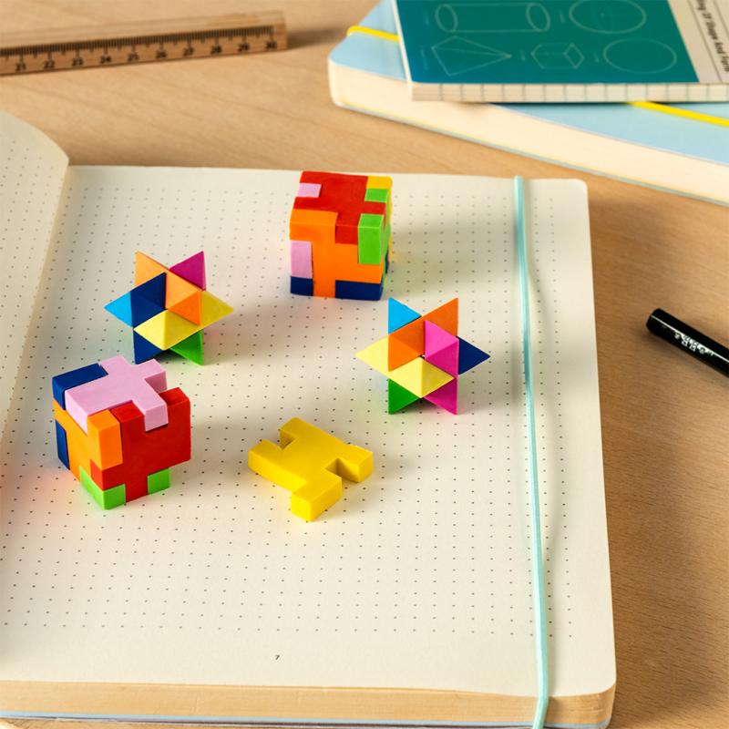 4 different shaped puzzle erasers laid out on a notebook.