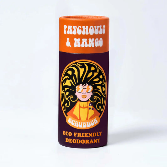 A Orange and maroon cardboard tube containing eco friendly deodorant. In the middle is an image of a woman wearing sunglasses and her hair forms the word 'scrubber' The text on the tube reads: 'Patchouli & mango - scrubber - eco friendly deodorant'  