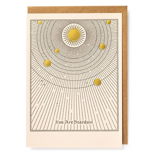 A white card with a golden sun at the top with 6 golden moon phases circling around. The text on the card reads: ' You are stardust'
