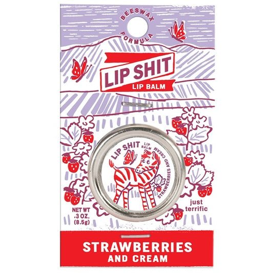 A Blue Q lip shit tin encased in purple cardboard packaging. The text reads: 'Lip shit lip balm Strawberries and cream'