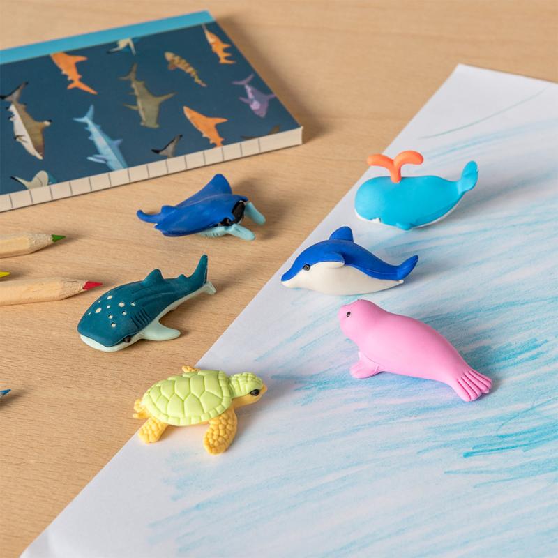 6 different ocean erasers laid out on top of a notebook.
