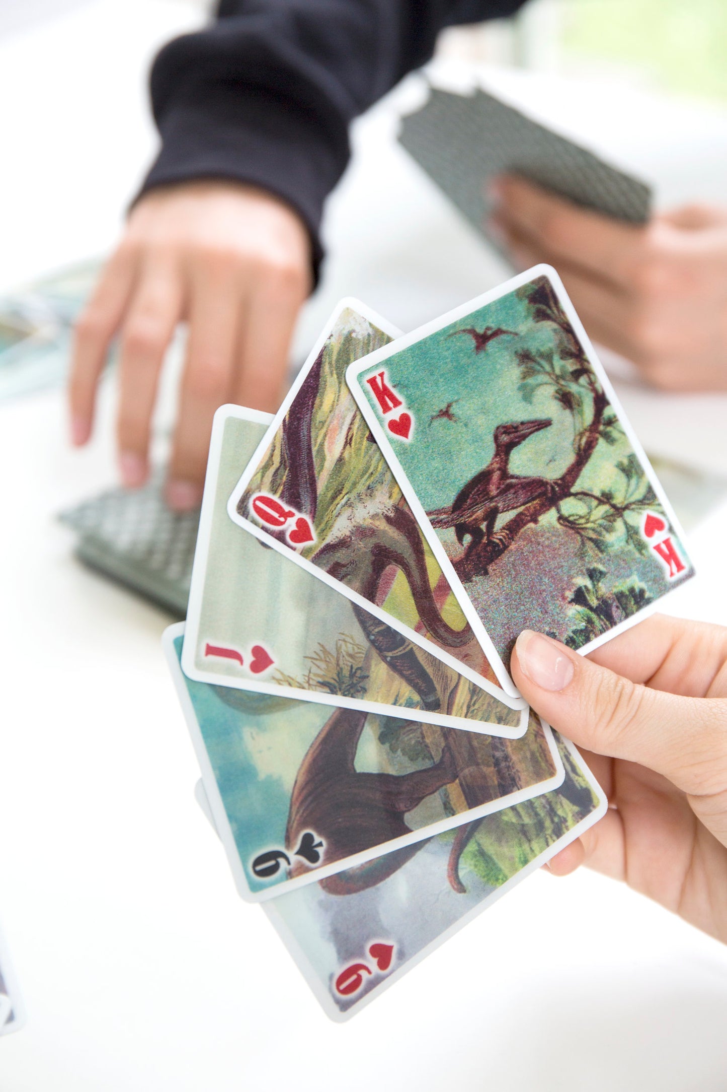 someone holding 4 different dinosaur lenticular playing cards.