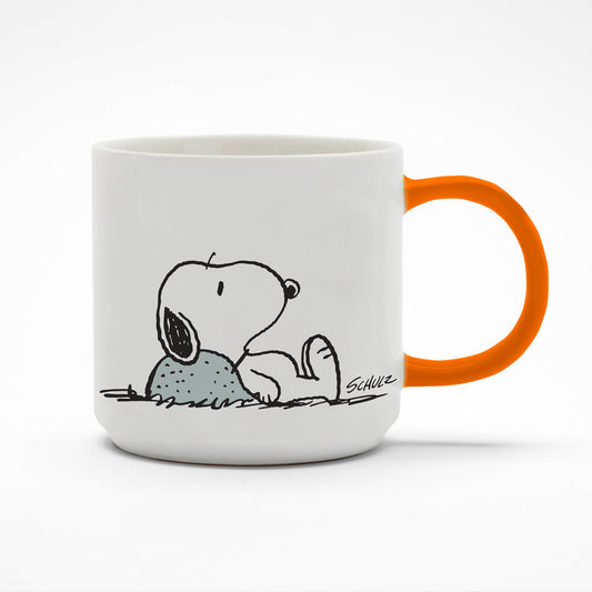 A white mug with an orange handle. On the mug is a graphic of Snoopy laying down with his head on a rock looking a little deflated.