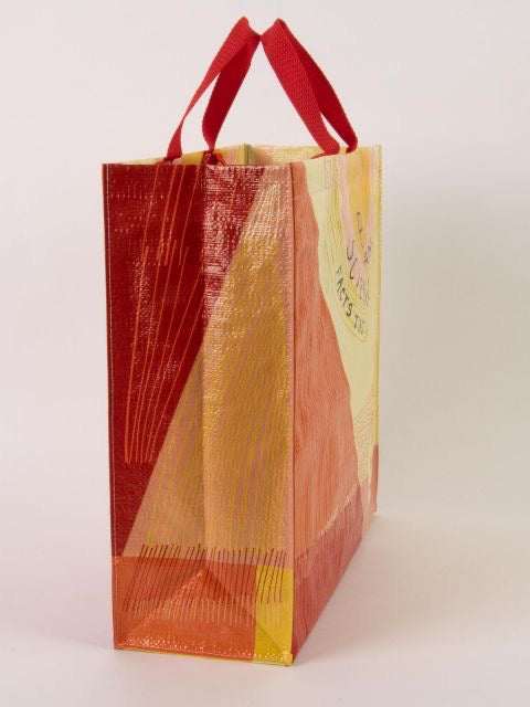 A yellow and orange Blue Q tote bag from the side. The bag has red handles and striped running up the side
