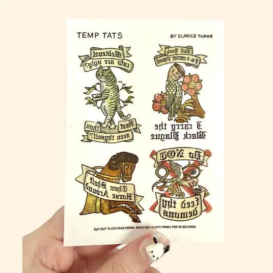 Set of temporary tattoos by Clarice Tudor held by a hand on a beige background