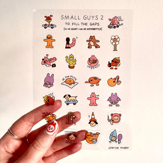Sheet of small illustrated characters stickers with a hand holding them.
