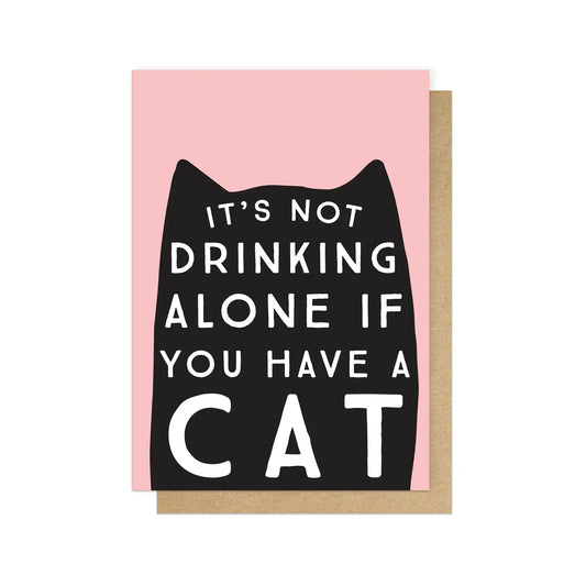 Card with black cat illustration and text on pink background. The card reads: It's not drinking alone if you have a cat