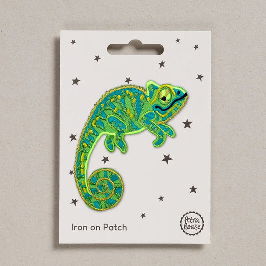 Embroidered chameleon patch on a white card with star patterns.
