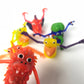 A group of six finger monster puppets of different shapes and sizes are sitting together on a white background.