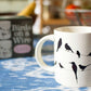 A cream mug with silhouettes of birds on a wire all over, when hot water is poured in they become colourful 