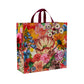 A floral tote bag with red handles. the flowers on the bag are Blue, red green yellow and pink. 