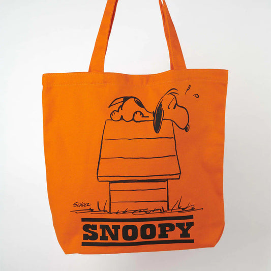 Bright orange canvas tote bag with print of Snoopy the Beagle dog lying down on top of the roof of his kennel. Text below image reads SNOOPY