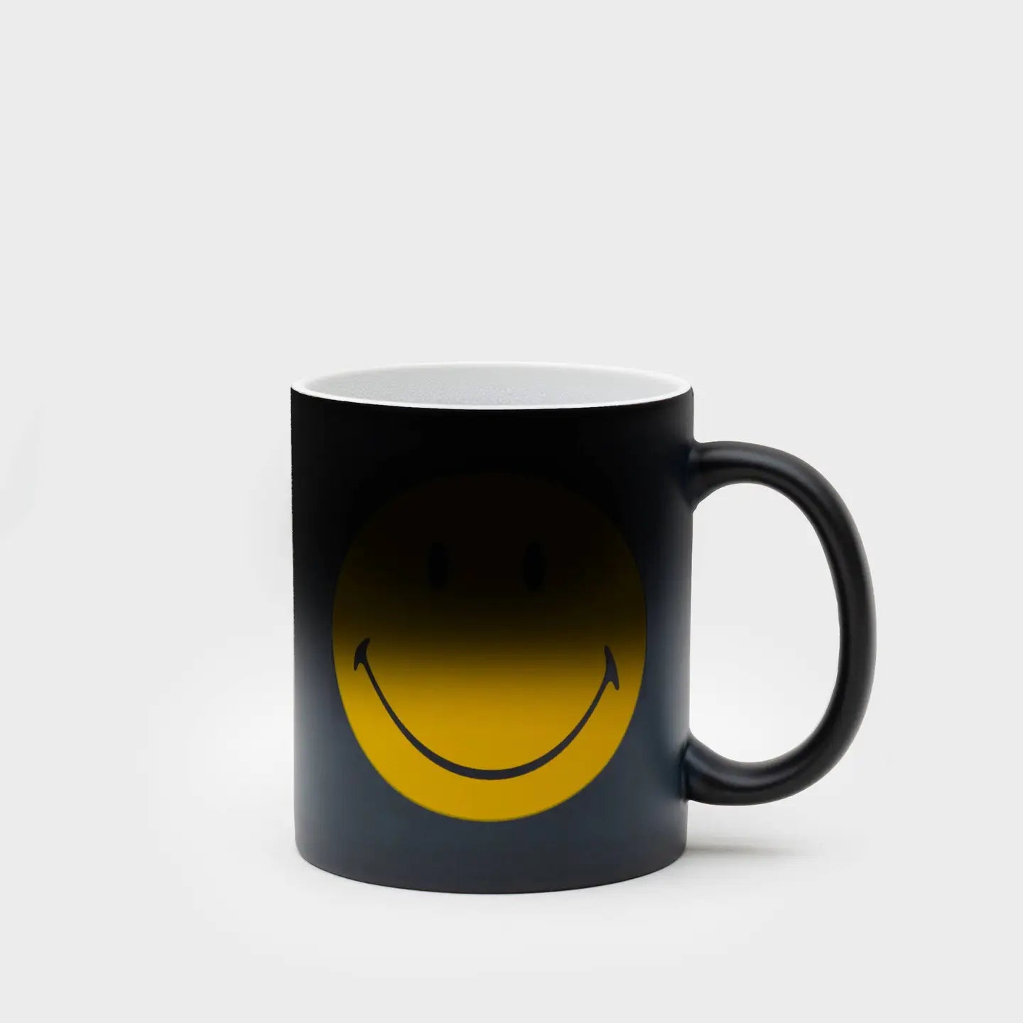 A black color changing mug with a smiley face design that becomes visible when the mug is heated.