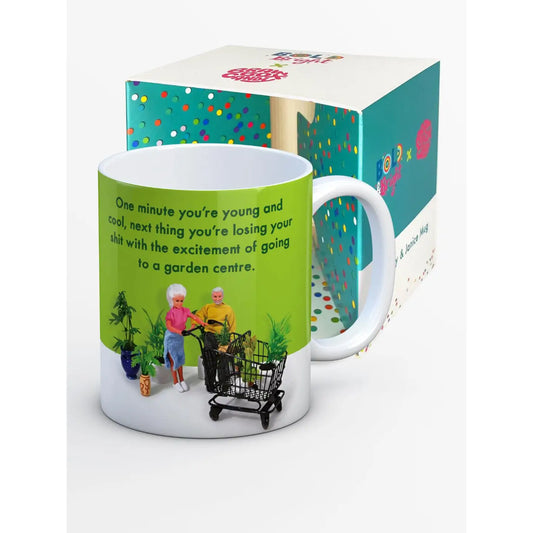 Mug with humorous design and text, displayed with a colorful box in the background.