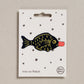 Fish-shaped iron on patch on a white card with star patterns, brand 'Petra Boase' visible.