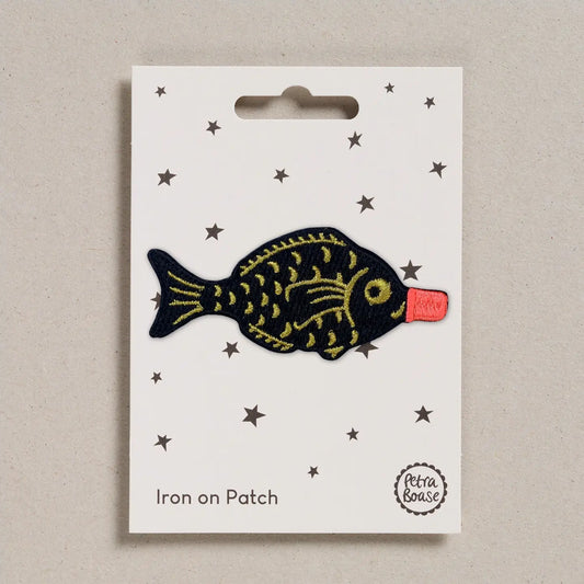 Fish-shaped iron on patch on a white card with star patterns, brand 'Petra Boase' visible.