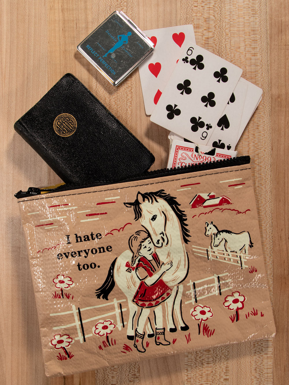 A brown, Blue Q zipper pouch with a girl in a red dress hugging a white horse. The text reads: ' I hate everyone too.'