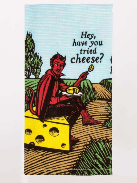 A Blue Q tea towel with the devil sat on a block of cheese in a field. The text reads: 'Hey, have you tried cheese?'