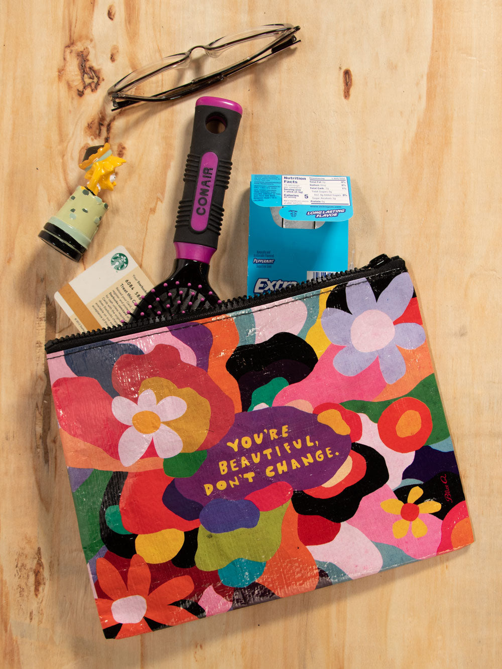 A Blue Q zipper pouch with multicoloured flowers and squiggles all over. The text reads: You're beautiful don't change
