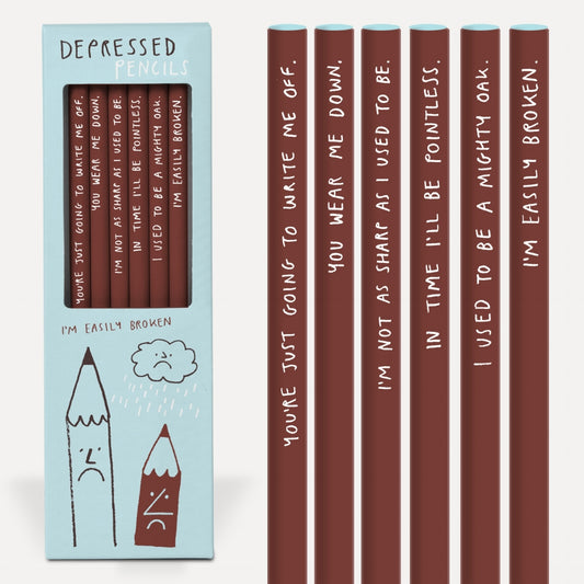A blue cardboard box with the graphic on the front of 2 sad cartoon pencils and a sad cloud. The box reads: Depressed pencils, I'm easily broken. To the side of the box are a set of pencils that read: You're just going to write me off, You wear me down, I'm not as sharp as i used to be, In time I'll be pointless, I used to be a mighty oak and I'm easily broken