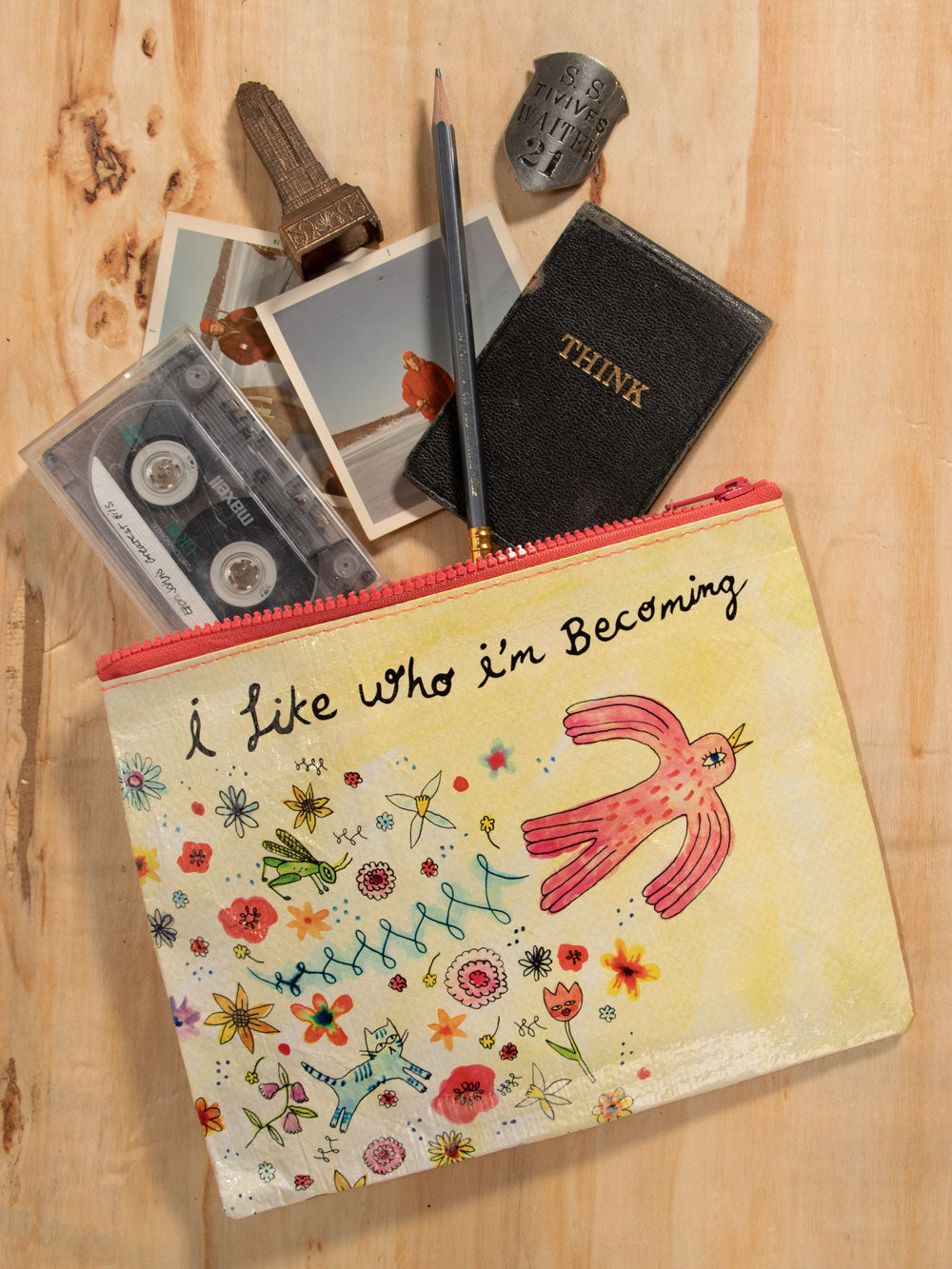 Yellow, Blue Q zipper pouch with a drawing of a red bird with colourful flowers. The text reads: I like who i'm becoming