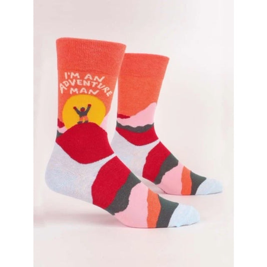 Orange and red men's Blue Q socks with a man walking over a mountain. The text above says 'i'm an adventure man'