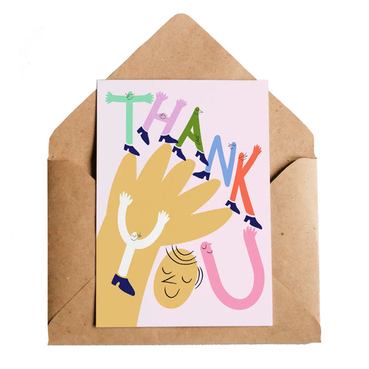 A pink card with a hand and a smiling face on the front. The text on the card reads: Thank you and the letters are made up of little stick people 